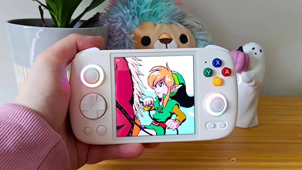 Ręka trzyma biały handheld, na ekranie gra Link. Idealny do retro games online emulator.